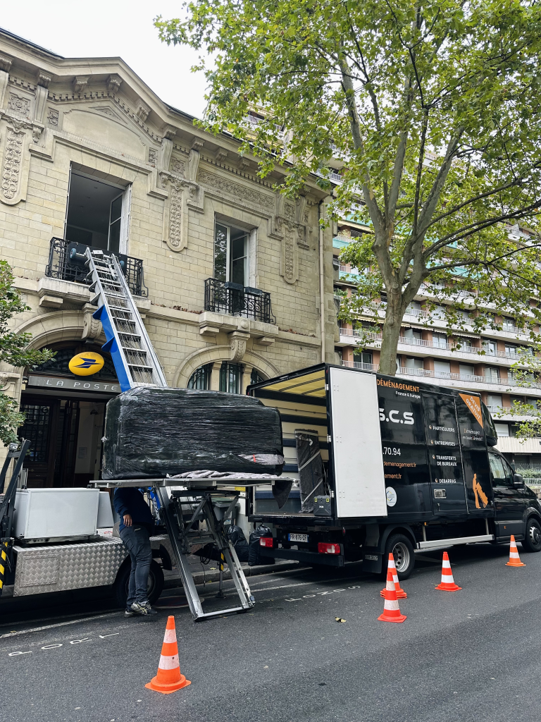 société de déménagement déchargent meuble imposant depuis le 1er étages à l'aide d'un monte meuble