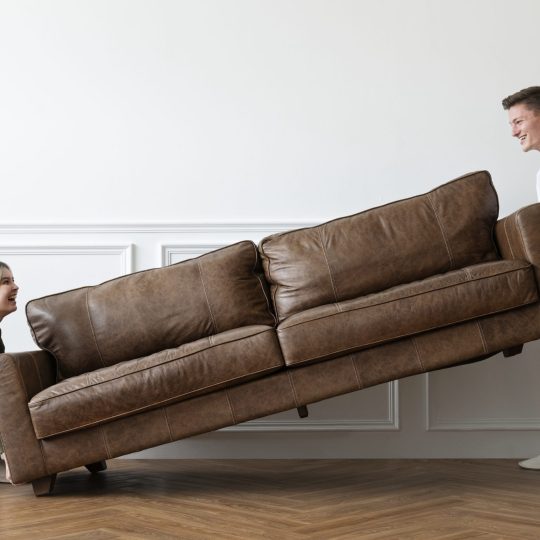 Couple moving a sofa in a new home