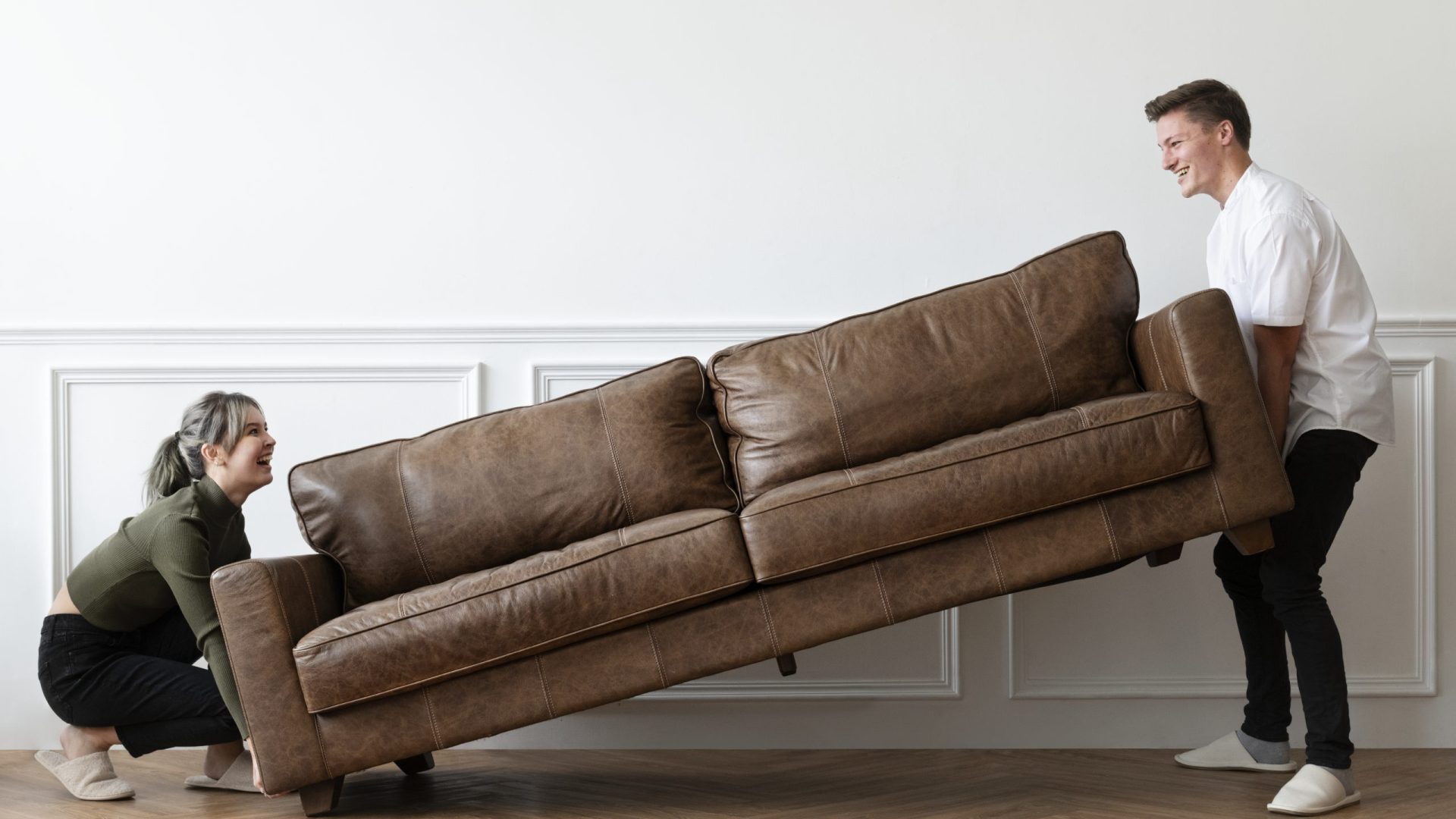 Couple moving a sofa in a new home